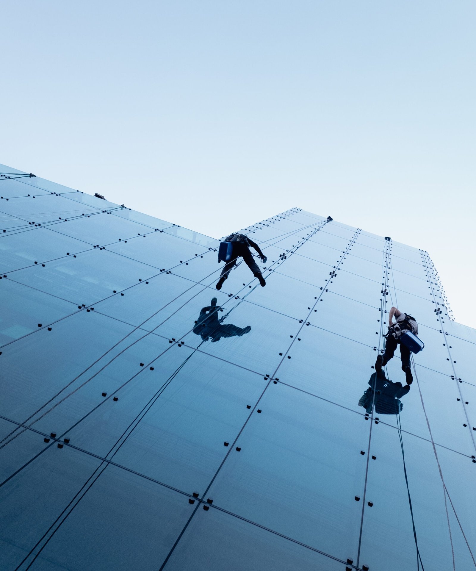 Low angle shot of two persons rappelling at the side of a tall building